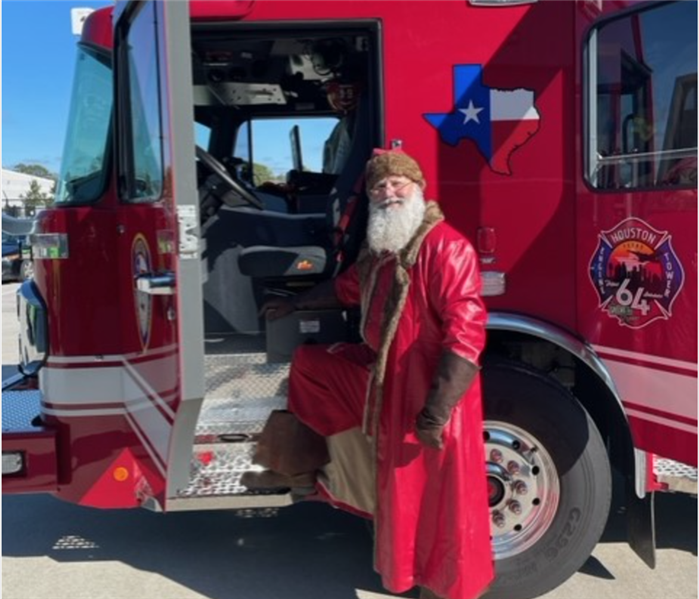 Santa posing in front of fire truck.