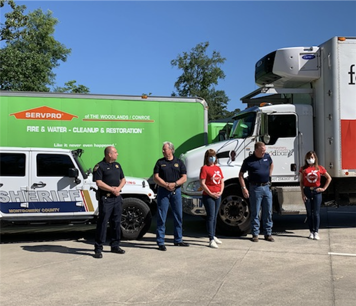 people standing in front of a white and red truck and a SERVPRO truck