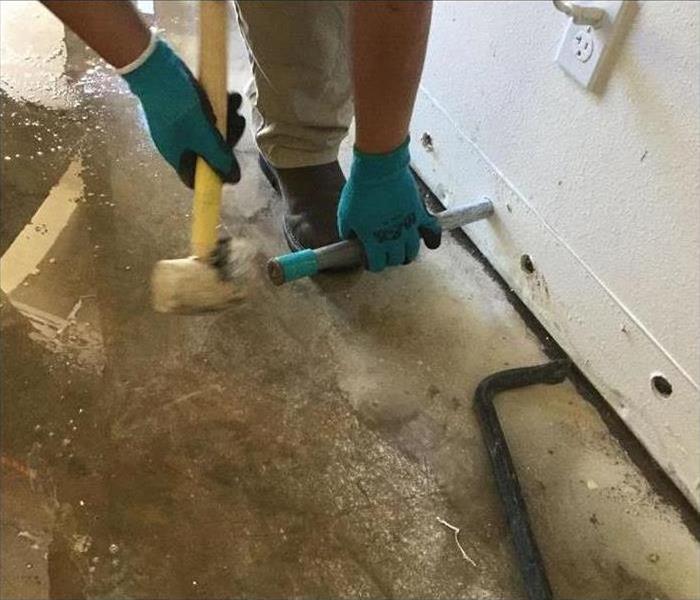 Man with a hammer making a hole on baseboards to introduce air equipment